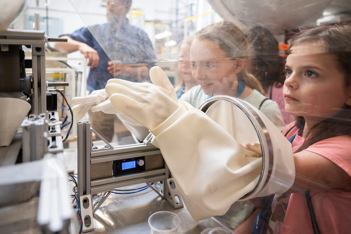 Girl enjoying a hands-on lab experience with much concentration while her friend watches in amazement.